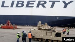 Ofițeri de vamă letoni inspectează un vehicul de luptă Bradley pentru trupele americane ce vor fi desfășurate în curînd în zonă