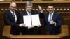 Зліва направо: спікер парламенту Андрій Парубій, президент Петро Порошенко і прем’єр-міністр Володимир Гроймсан на трибуні Верховної Ради з підписаним главою держави законом про зміни до Конституції, які закріплюють курс України на ЄС і НАТО. Київ, 19 лютого 2019 року