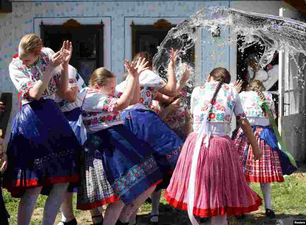 Юные девушки в традиционной одежде реагируют на то, как мужчины обливают их водой во время традиционного пасхального празднования в Чёмёре, Венгрия, 21 апреля 2025 года. REUTERS/Bernadett Szabo
