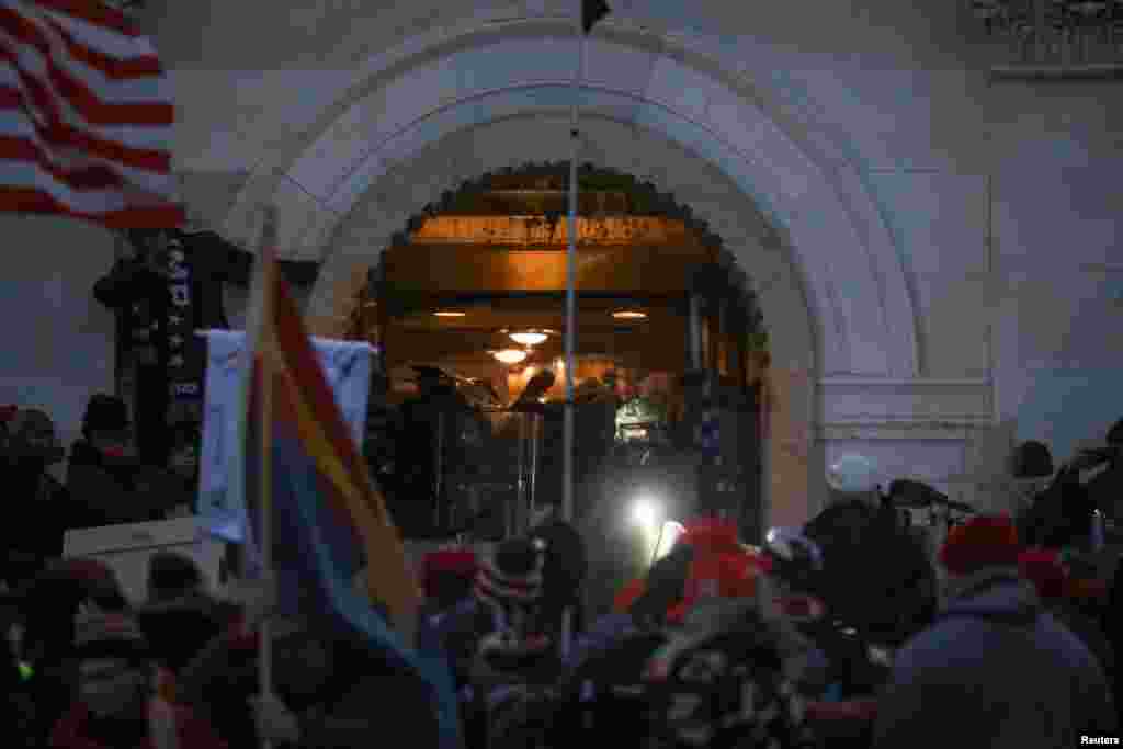 Oficerët e policisë mbrohen me mburojat e tyre ndërsa përpiqen t&#39;i mbajnë mbështetësit e Trumpit jashtë ndërtesës së Kongresit gjatë një proteste kundër certifikimit të rezultateve të zgjedhjeve presidenciale të nëntorit 2020, Uashington, janar 2021.