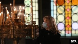 Жена пали свещ в катедралата "Александър Невски" на 25 декември по време на коледната литургия. 