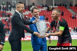 Szijjártó Péter és Bánki Erik átadják a másodosztályú bajnoki serleget Dzsudzsák Balázsnak, a DVSC csapatkapitányának, 2021. május 16-án.