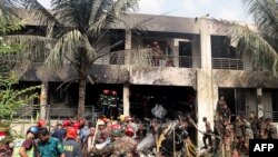 Pompierii și personalul de securitate din Bangladesh verifică o clădire după ce un avion de antrenament al Forțelor Aeriene s-a prăbușit într-o școală din Dhaka, pe 21 iulie 2025.