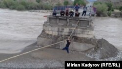 Жители Ак-Талинского района перебираются на противоположный берег по веревке.