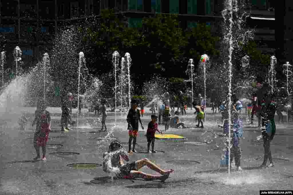 Децата и возрасните се разладуваат на плоштадот Андре-Ситроен во француската престолнина на 29 јуни.