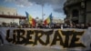 În Piața Univeristății, protestatarii au un banner pe care scrie „Libertate”