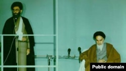 آیت‌الله روح‌الله خمینی (نشسته)، بنیانگذار جمهوری اسلامی ایران و آیت الله علی خامنه ای، رهبر فعلی ایران