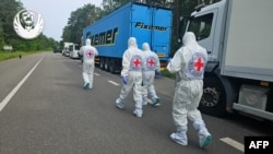 Fotografie publicată în 11 iunie, de Comitetul de coordonare a schimbului de prizonieri de război Rusia-Ucraina, cu reprezentanți ai Crucii Roșii care merg pe lângă un convoi frigorific care a transportat cadavre ale soldaților ucraineni.