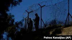 Dve osobe stoje iza ograde na delu Kipra pod turskom okupacijom, gledajući na tampon zonu UN koja deli grčki od turskog dela ostrva, 8. decembar 2024.