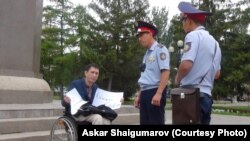 Полицейские разговаривают с Эриком Жумабаевым во время проведения им акции протеста с требованием освободить политзаключенных. Уральск, 12 августа 2019 года.