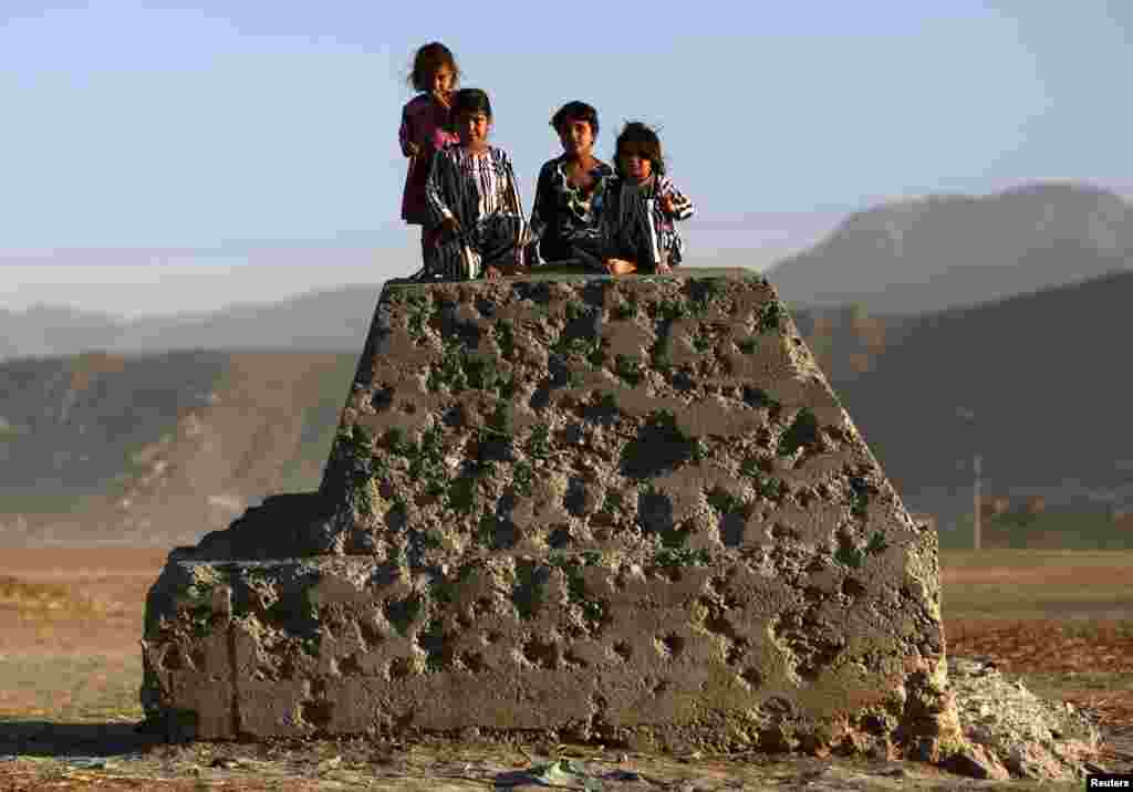 Афганские дети сидят на бетонной конструкции, испещренной пулями, - Кабул.