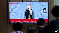 Pasageri din Gara Seul, în Coreea de Sud, trec pe lângă un ecran pe care sunt difuzate imaginile cu Kim Jong Un la instalația de îmbogățire a uraniului, pe 13 septembrie 2024.