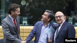 Новий міністр фінансів Греції Ефклідіс Цакалотос (с) на зустрічі голів мінфінів єврозони у Брюсселі 7 липня 2015 року; його вітають голова Єврогрупи Єрун Дейсселблум (л) і міністр фінансів Франції Мішель Сапен (р)