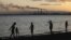 Residents walk the shore of Lake Balkhash at dusk, in front of the city's 1930s-built copper smelter owned by Kazakhmys copper mining company in the city of Balkhash.