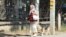 O pensionară echipată cu mască și însoțită de un câine la plimbare prin Bălți