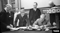 Міністр закордонних справ СРСР В'ячеслав Молотов (праворуч, сидить) підписує пакт Молотова-Ріббентропа. Третій ліворуч – генеральний секретар ЦК ВКП(б) Йосип Сталін. Москва, 23 серпня 1939 року 