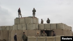 Afghan soldiers stand at a checkpoint in Kunduz where clashes took place between Taliban and Afghan forces amid a recent flare-up in deadly violence.