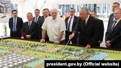 ბელარუსის პრეზიდენტი ალექსანდრ ლუკაშენკა (ცენტრში) ბელარუსის ბიოტექნოლოგიურ კორპორაციაში. ყირგიზეთი აცხადებს, რომ მამაკაცი, რომელიც მის გვერდზე დგას (ჯოხით ხელში), არის ყირგიზეთის ყოფილი პრემიერ-მინისტრი, ძებნილი დანიარ უსენოვი. მინსკი, 2020 წ. 10 აგვისტო.