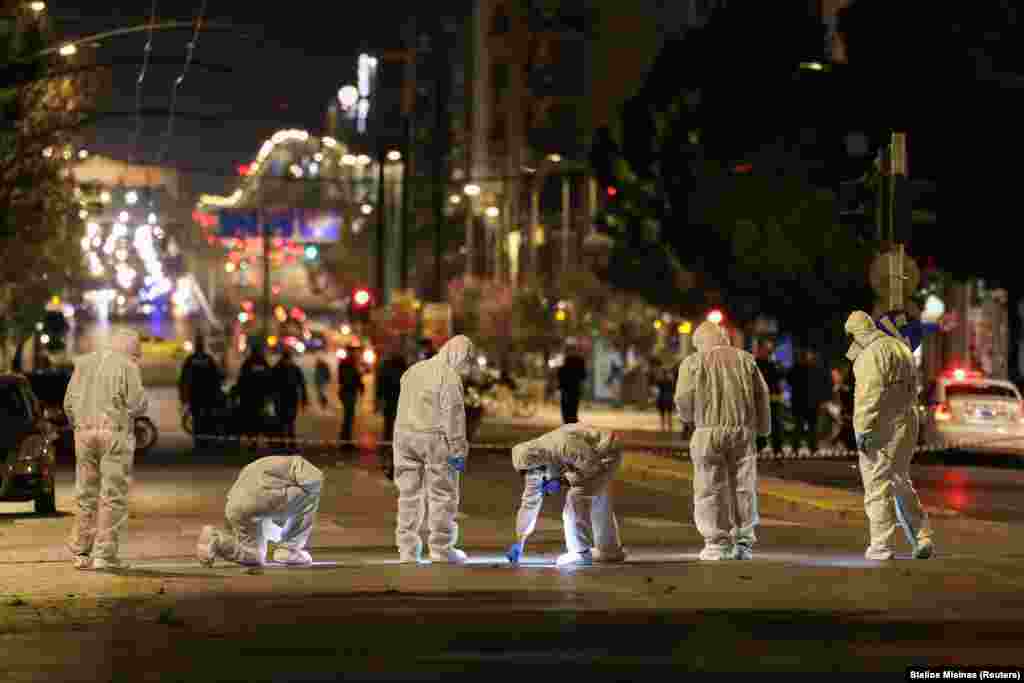 Сотрудники судебно-медицинской экспертизы проводят расследование на месте взрыва бомбы у офиса Hellenic Train в Афинах, Греция, 11 апреля. REUTERS/Stelios Misinas