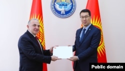 Түркиянын элчиси Мекин Мустафа Кемал Өкем (солдо) Кыргызстандын тышкы иштер министринин орун басары Медер Абакировго ишеним грамотасын тапшырып жатат. Бишкек. 7-апрель, 2025-жыл. 