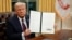 Президент США Дональд Трамп демонстрирует один из указов, подписанных им после инаугурационных торжеств 20 января
