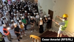 Inginerul Matei Sumbasacu (dreapta) le explică spectatorilor de ce a fost importantă întâlnirea care a avut loc în acest spațiu pe 4 iulie 1977, când Nicolae Ceaușescu a decis sistarea lucrărilor de consolidare la clădirile afectate de cutremur