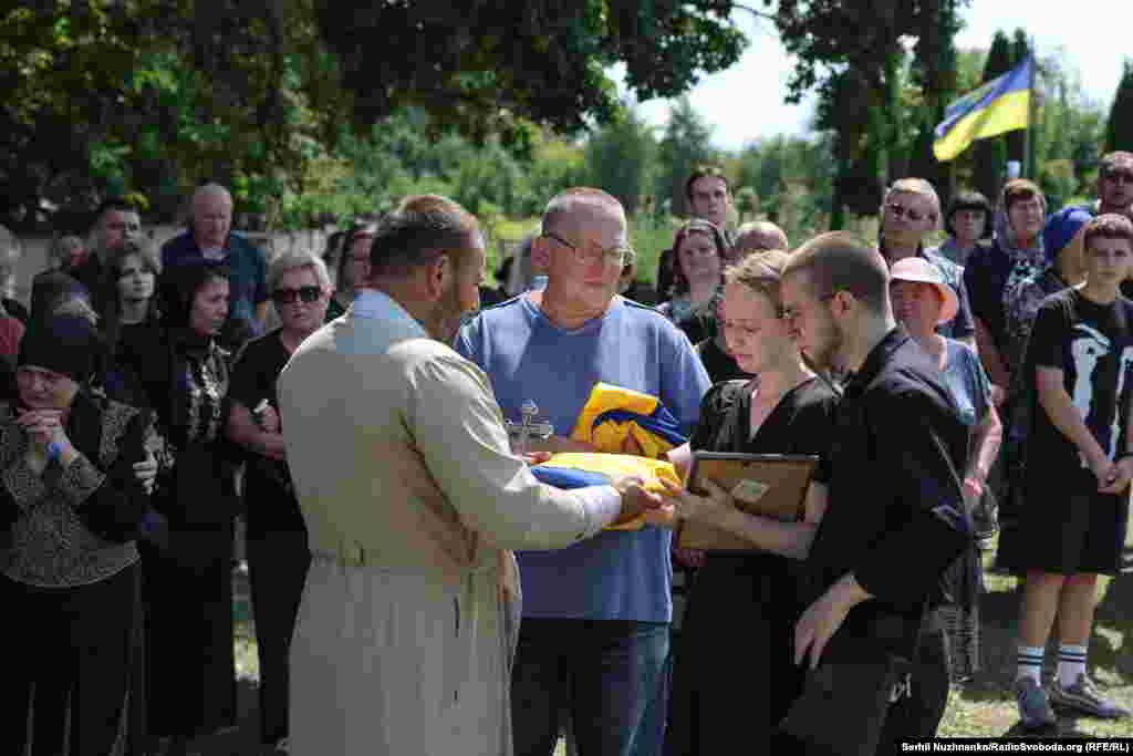 Священник передає близьким прапори, якими були вкриті домовини