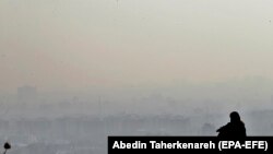 Egy magányosan üldögélő iráni lány nézi Teherán látképét a Darabad-hegyről 2020. október 16-án.