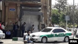 Journalists and police crouch near the Iranian parliament in the capital Tehran during an attack on the complex that left at least a dozen people dead. 