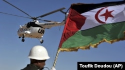 هلی‌کوپتر حامل دبیرکل وقت سازمان ملل در پس‌زمینه پرچم جمهوری دموکراتیک عربی صحرا در یکی از کمپ‌های پناهچویان صحرا در الجزایر/ مارس ۲۰۱۶