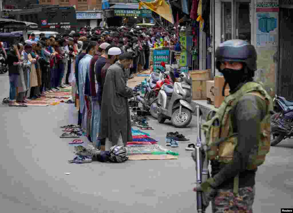 Кашмирские мусульмане совершают пятничную молитву на дороге, в то время как сотрудники службы безопасности стоят на страже, в Сринагаре, 2 мая 2025 года. REUTERS/Adnan Abidi