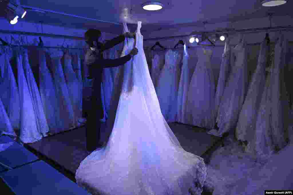 Un negustor aranjează o rochie de mireasă, expusă într-un magazin de confecții pentru femei din Kabul. &nbsp;