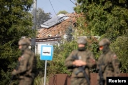Польські вояки на вулицях села Вирикі в східній Польщі на тлі будинку, що зазнав руйнувань внаслідок російської дронової атаки 10 вересня 2025 року