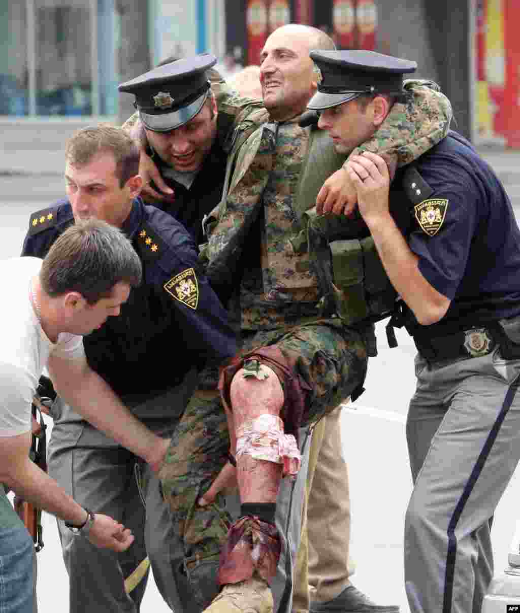 Полицейские оказывают помощь грузинскому солдату, раненому в бою с южноосетинскими сепаратистами в Гори. 8 августа 2008 года &nbsp;