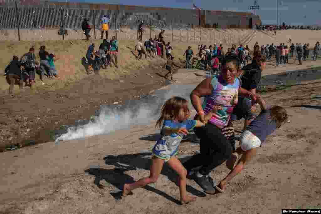 Maria Meza, a 40-year-old migrant woman from Honduras, runs away from tear gas with her 5-year-old twin daughters Saira Mejia Meza (left) and Cheili Mejia Meza (right) in front of the border wall between the United States and Mexico, in Tijuana, Mexico, November 25, 2018.(Reuters/Kim Kyung-hoon)