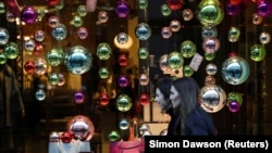 Járókelők sétálnak a londoni Regent Streeten lévő karácsonyi kirakatok előtt.