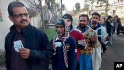 Хората държат националните си карти за самоличност, докато чакат реда си да гласуват пред избирателна секция по време на парламентарните избори в Мултан, Пакистан, четвъртък, 8 февруари 2024 г.