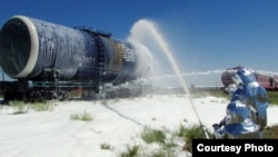 Сотрудники противопожарной службы ЧС обрабатывают цистерну с горючим специальной пеной, чтобы не произошло возгорания.  Таможенный пункт "Куланды", Жамбылская область, 16 июля 2014 года. Фото предоставлено ДЧС Жамбылской области.