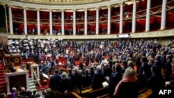 Francia baloldali képviselők felállva tiltakoznak a törvény ellen a parlamentben Párizsban 2023. december 19-én