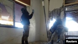UN chemical weapons experts, wearing gas masks, inspect one of the sites of an alleged chemical weapons attack in a Damascus suburb earlier this year. 