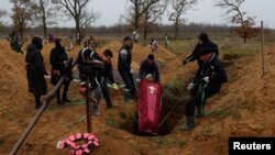 Siciriul unui localnic numit Artiom, care a murit în timpul ocupației ruse, este coborât în groapă la Herson, 27 noiembrie 2022.