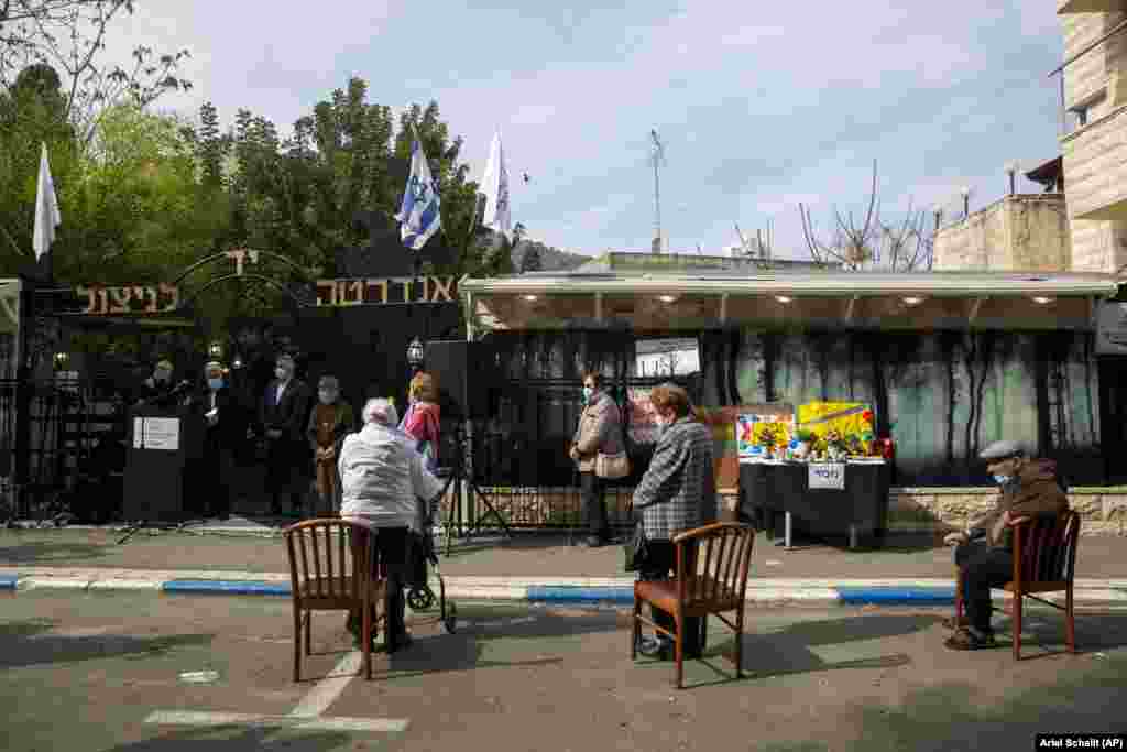 Të mbijetuarit e Holokaustit mbajnë maska në fytyrë, si dhe mbajnë distancë nga njëri-tjetri derisa marrin pjesë në ceremoninë vjetore në Ditën Ndërkombëtare të Përkujtimit të Holokaustit që sivjet po mbahet në ambiente të hapura për shkak të pandemisë së koronavirusit. Qyteti verior i Izraelit Haifa, 27 janar 2021.&nbsp;
