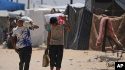 Palestinezët duke bartur ushqim dhe ndihmë humanitare të shpërndarë nga GHF-ja. 28 maj 2025. 