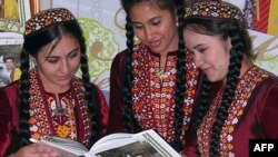 Туркменские девушки смотрят фотографии из новой книги об Ахалтекинских аргамаках (на обложке - фотография президента Гурбангулы Бердымухамедова). Ашгабат. 21 апреля 2011 г. AFP.