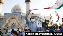 Supporters of Iranian presidential candidate Ebrahim Raisi hold pictures depicting him during an election campaign rally in Tehran, on June 16.