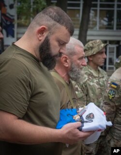 Мамука Мамулашвілі на траурній церемонії тримає прапор підрозділу з нагородами свого побратима Закарії Шубітідзе, який загинув обороняючи Україну. Київ, 21 вересня 2023 року