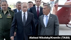 Russian President Vladimir Putin (left) walks with Tatarstan President Rustam Minnikhanov (right) and other officials on a visit to Kazan in May 2019. Soon, only one will be president.