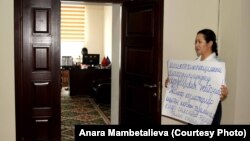 Анара Мамбеталиева в здании Госэкотехинспекции вышла на акцию с плакатом в руках.