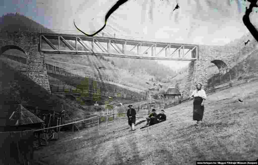 Localnici și un pod de cale ferată peste râul Trotus în 1908. Szocs a declarat pentru RFE / RL că a început proiectul împreună cu cei doi prieteni din liceu și cu un buget de &bdquo;zero&rdquo;. El spune că arhiva funcționează momentan fără finanțare datorită relațiilor personale. Un alt prieten din copilărie care conduce o companie web găzduiește gratuit baza de date.