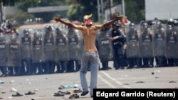 Після сутичок на кордоні Венесуели (позаду, за лавами венесуельської поліції) і Колумбії, з якої йде прихильник венесуельської опозиції, фото 23 лютого 2019 року